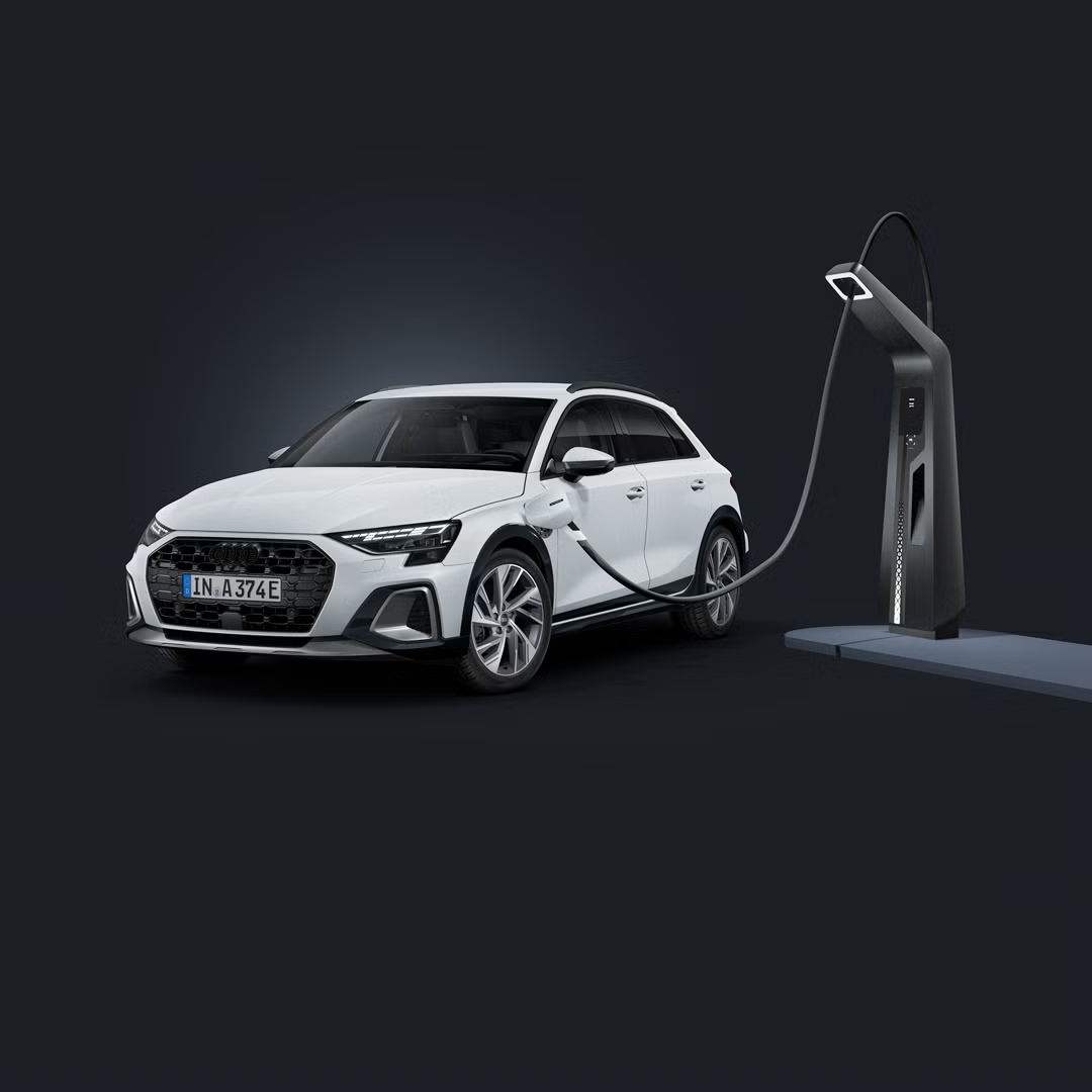 Der Audi A3 allstreet e-hybrid schräg von vorn auf dunklem Hintergrund, angeschlossen an eine moderne Ladesäule. 
