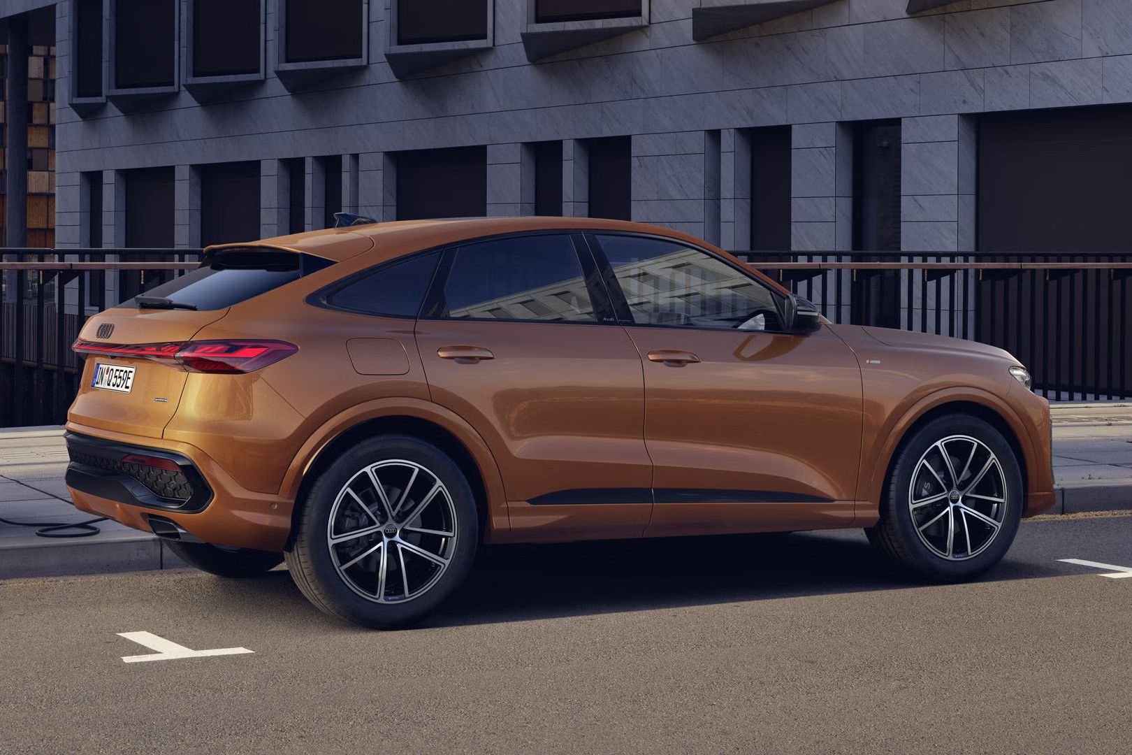 Der Q5 Sportback mit der Individuallackierung Ipanembraun Metallic steht auf einer Brücke und ist an eine Ladestation angeschlossen.