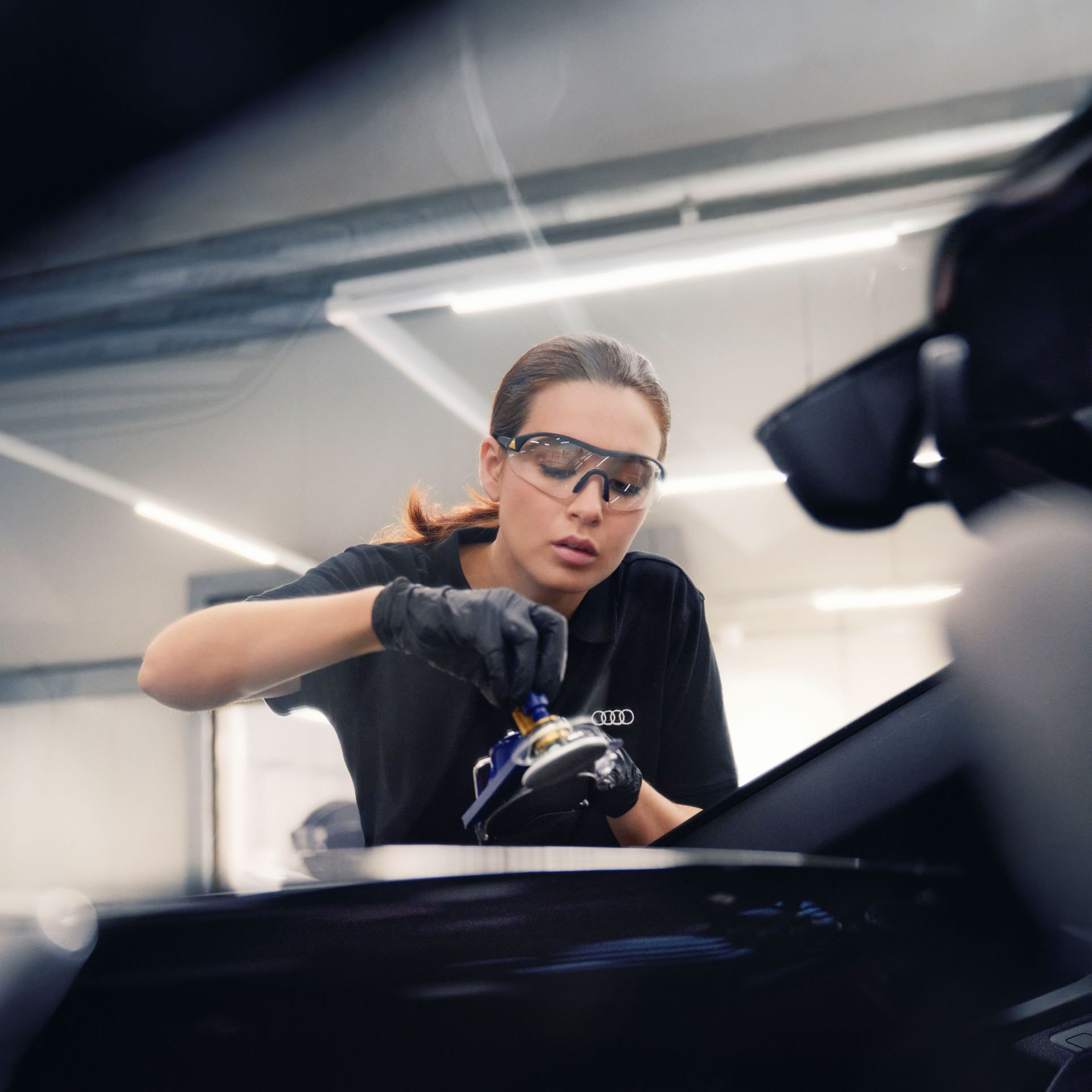 Eine Audi Mechanikerin bei der Reparatur einer Windschutzscheibe