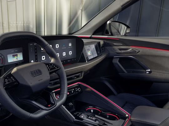 Blick in das Cockpit des SQ5 Sportback durch das Fahrerfenster. Zu sehen sind die verschiedenen Displays im Cockpit, sowie die rote Ambiente Beleuchtung.