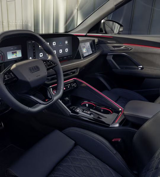 Blick in das Cockpit des SQ5 Sportback durch das Fahrerfenster. Zu sehen sind die verschiedenen Displays im Cockpit, sowie die rote Ambiente Beleuchtung.