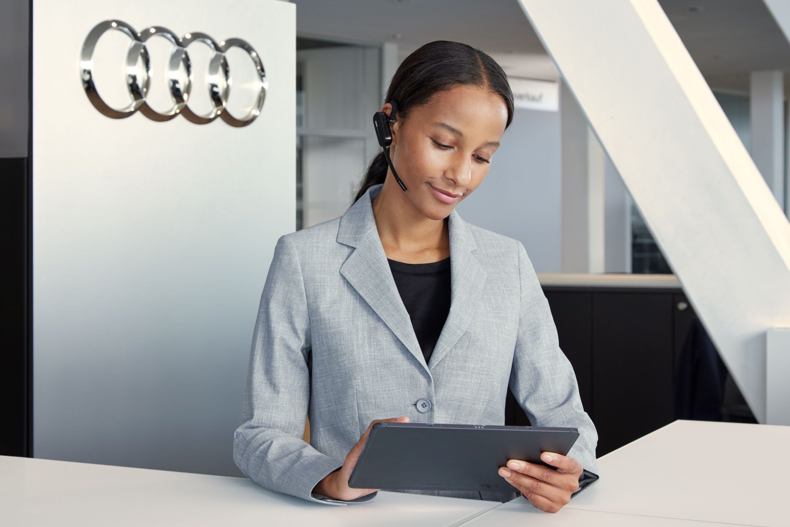 Eine Audi Service Mitarbeiterin blickt auf ihr Tablet