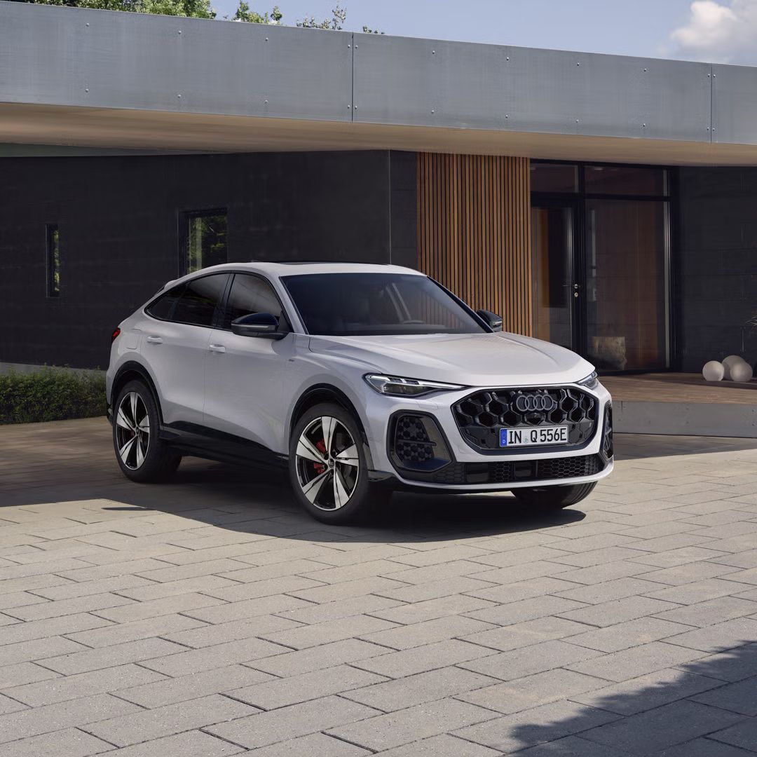 Die weiße Edition One mit mythosschwarzen Akzenten des Q5 Sportback e-hybrid parkt vor einem modernen Haus.