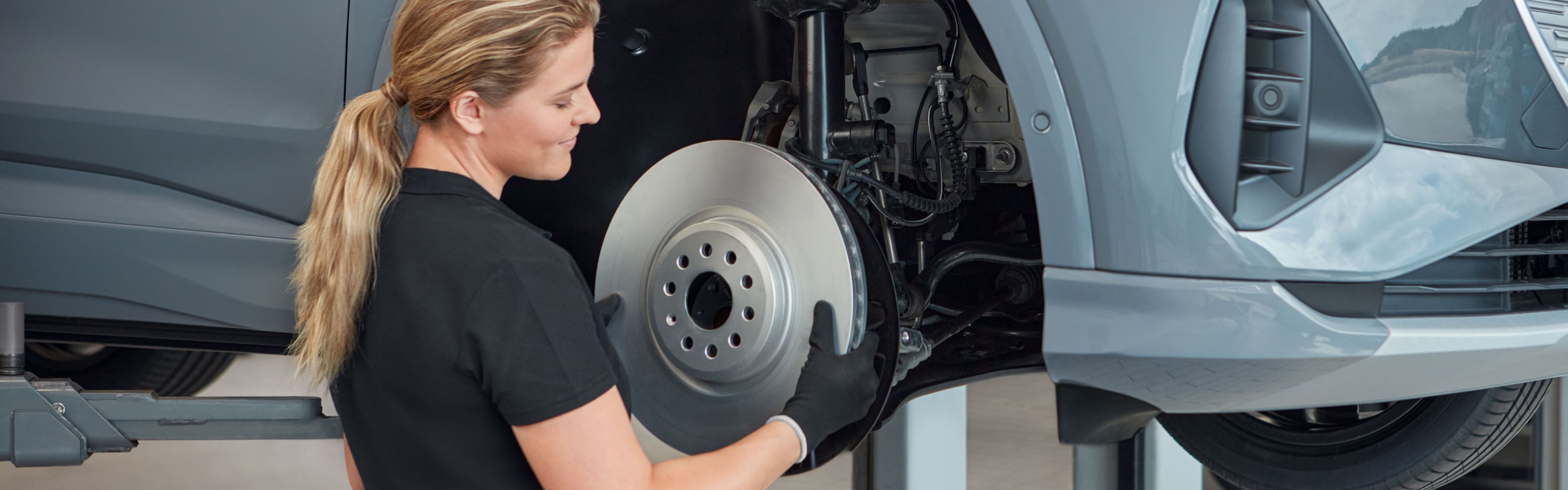 Eine Audi Service Technikerin wechselt die Bremsscheiben bei einem Audi Elektroauto