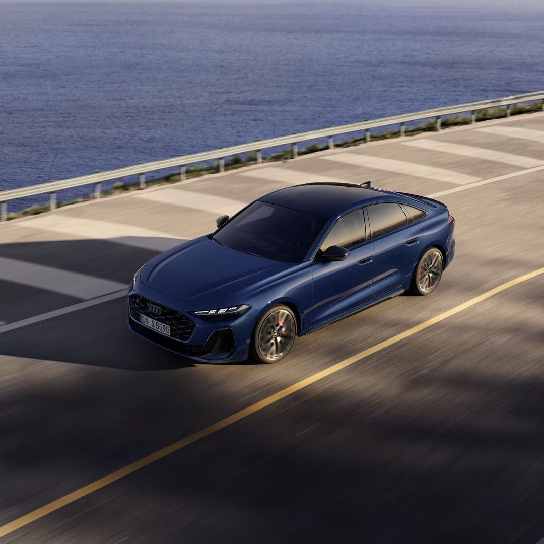 Die S5 Limousine von schräg oben. Sie fährt auf einer Straße entlang der Küste. 