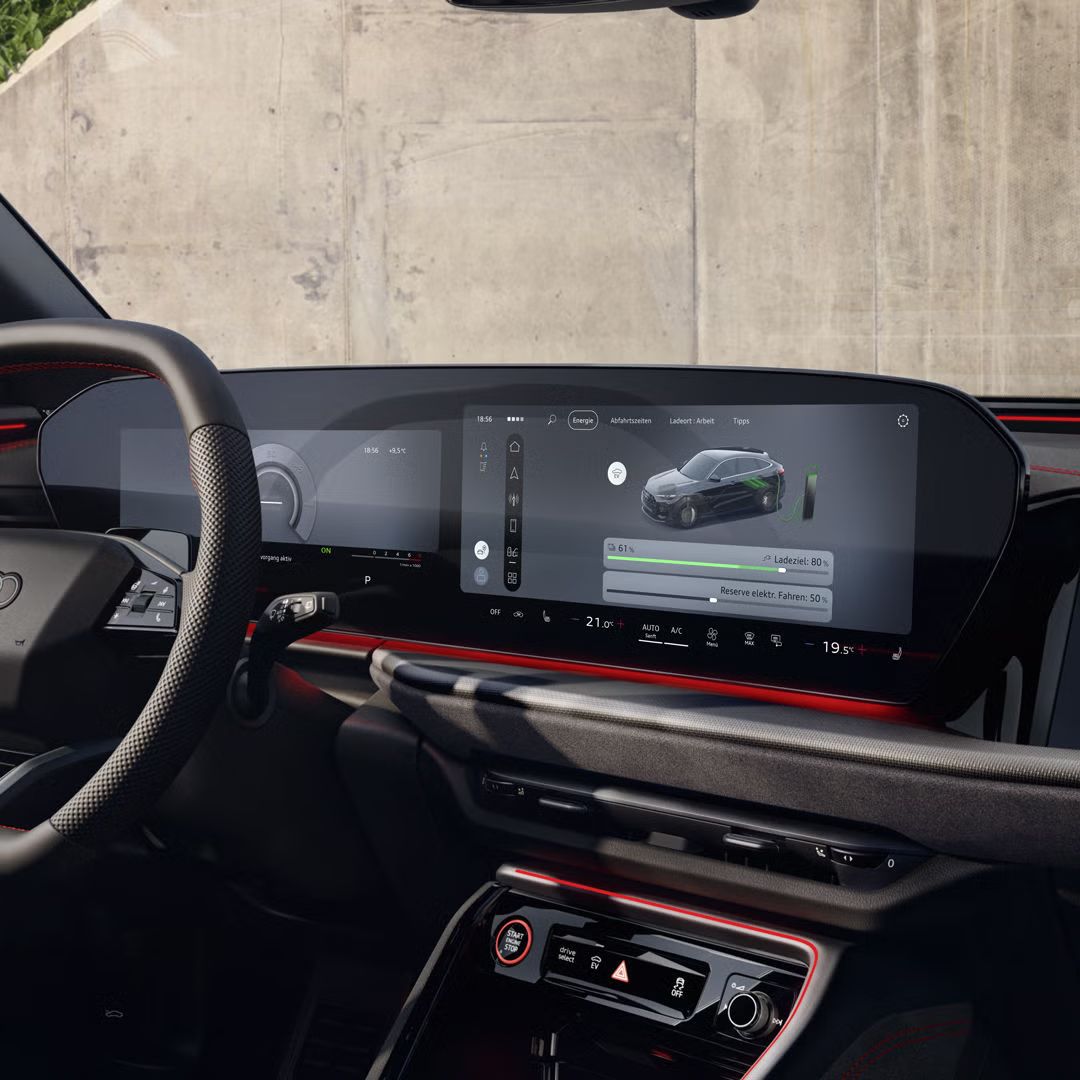 Der Innenraum des Q5 Sportback e-hybrid mit Fokus auf das Lenkrad und die digitalen Displays. Vor dem Fahrzeug steht eine modisch gekleidete, junge Frau.