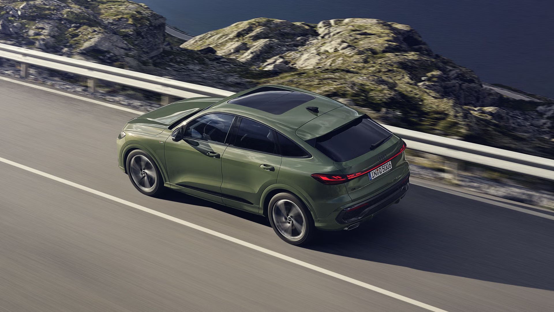 Der Q5 Sportback im schrägen Seitenprofil von oben betrachtet. Das Fahrzeug fährt auf einer Gebirgsstraße.