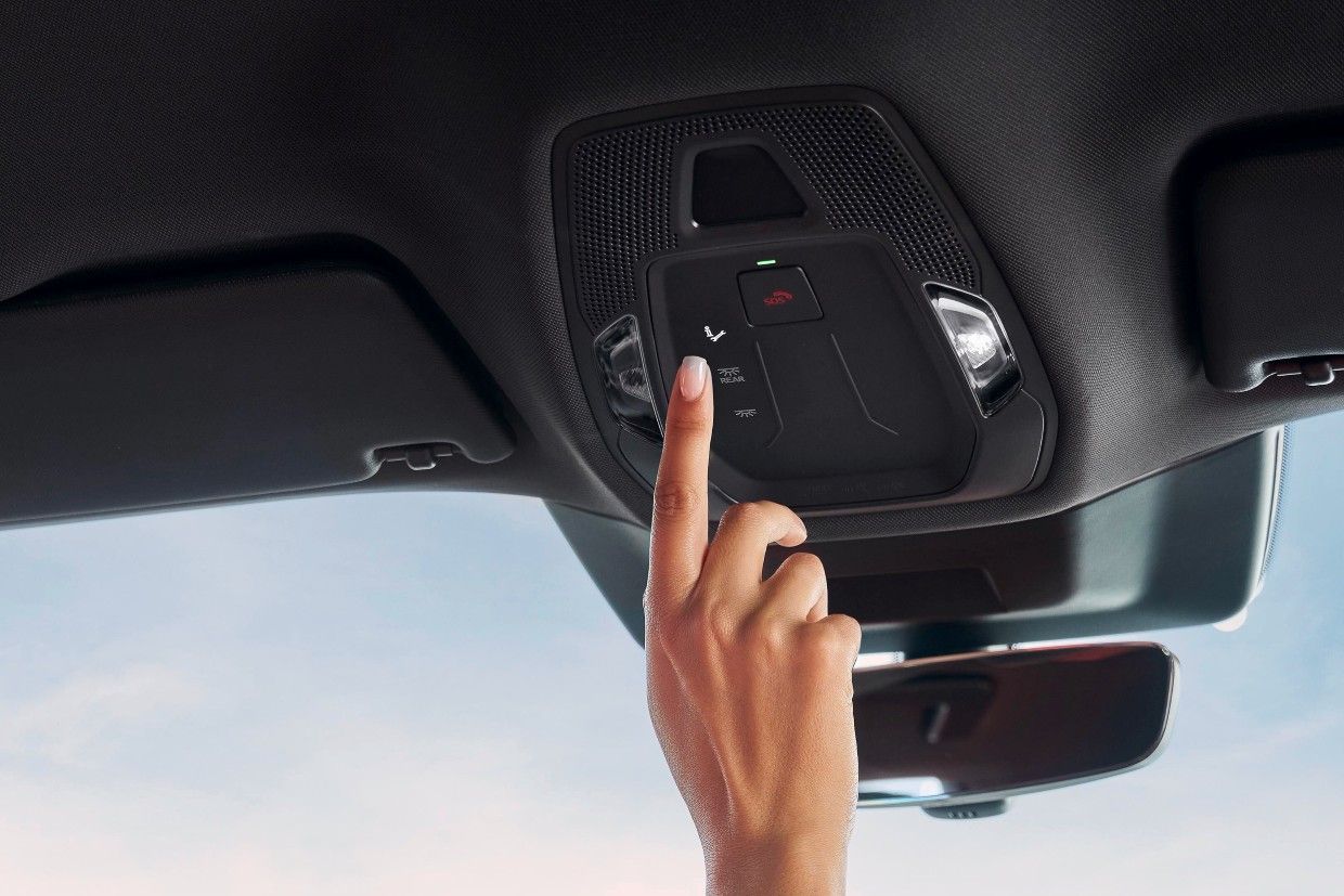 Hand der Audi Fahrerin bedient den Pannenhilfe Knopf im Fahrzeugdach