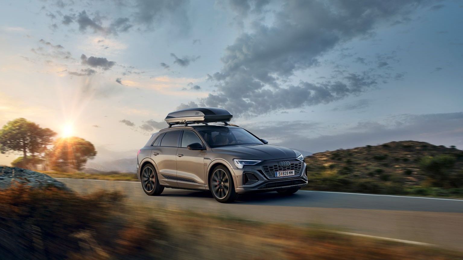 Ein Audi Q8 mit Dachbox in Fahrt auf einer Landstraße.