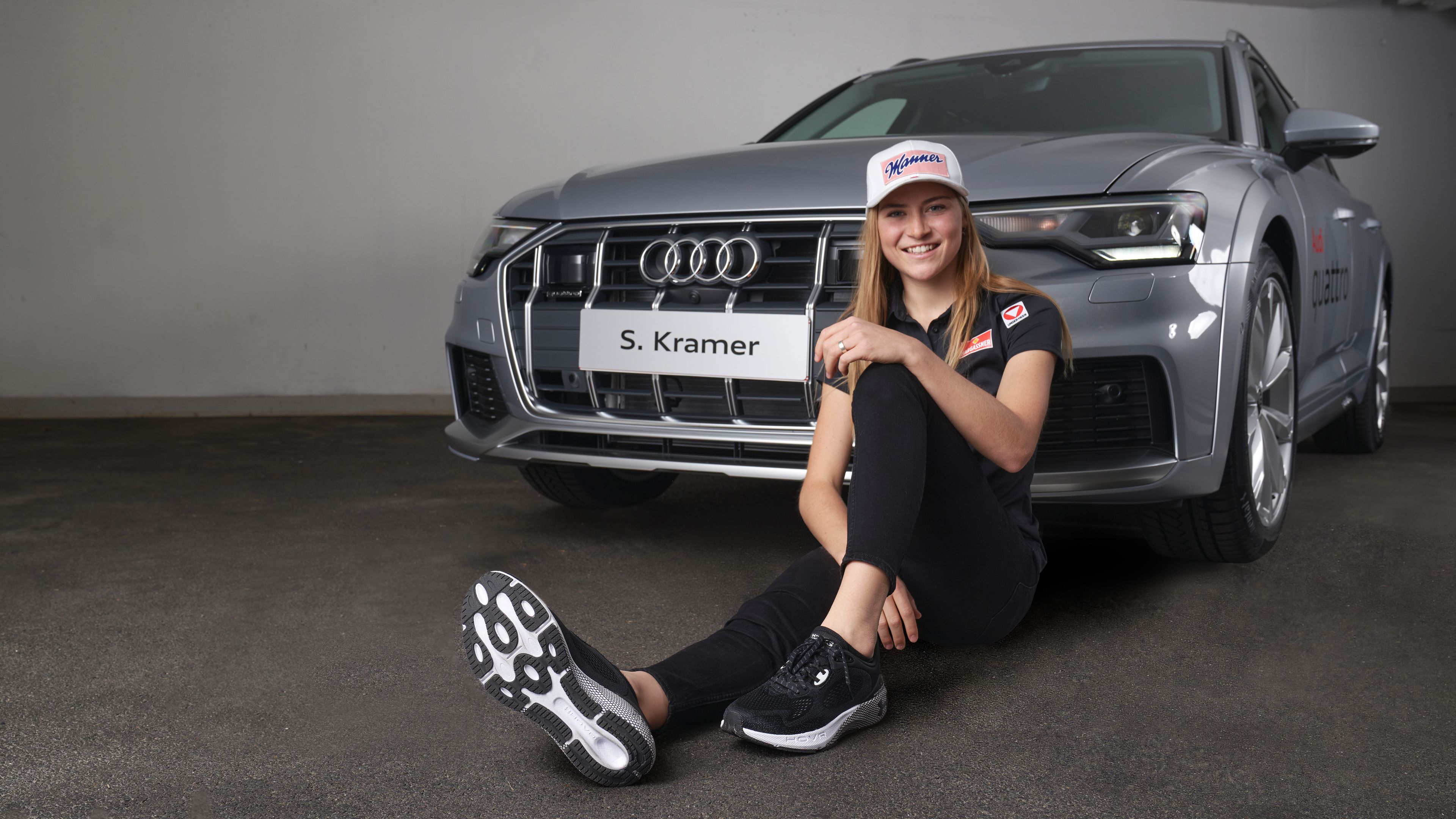 Skispringerin Sara Marita Kramer sitzt vor einem grauen Audi.