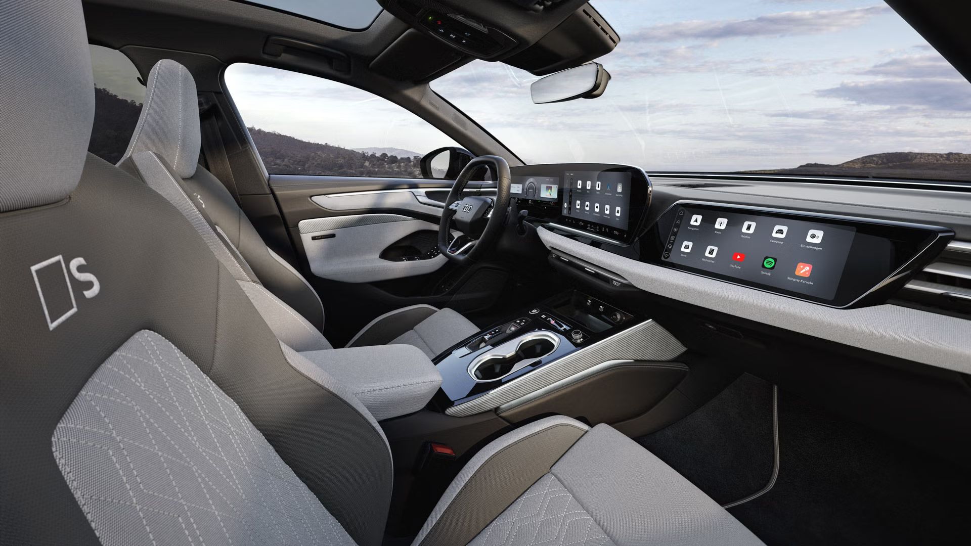 Der Innenraum der A6 Limousine e-hybrid aus der Sicht der Beifahrer B-Säule. Der Fokus liegt auf den Sportsitzen aus dem Stoff hellgrau-neodymgold mit Dekoreinlagen Leinengewebe in hellgrau.