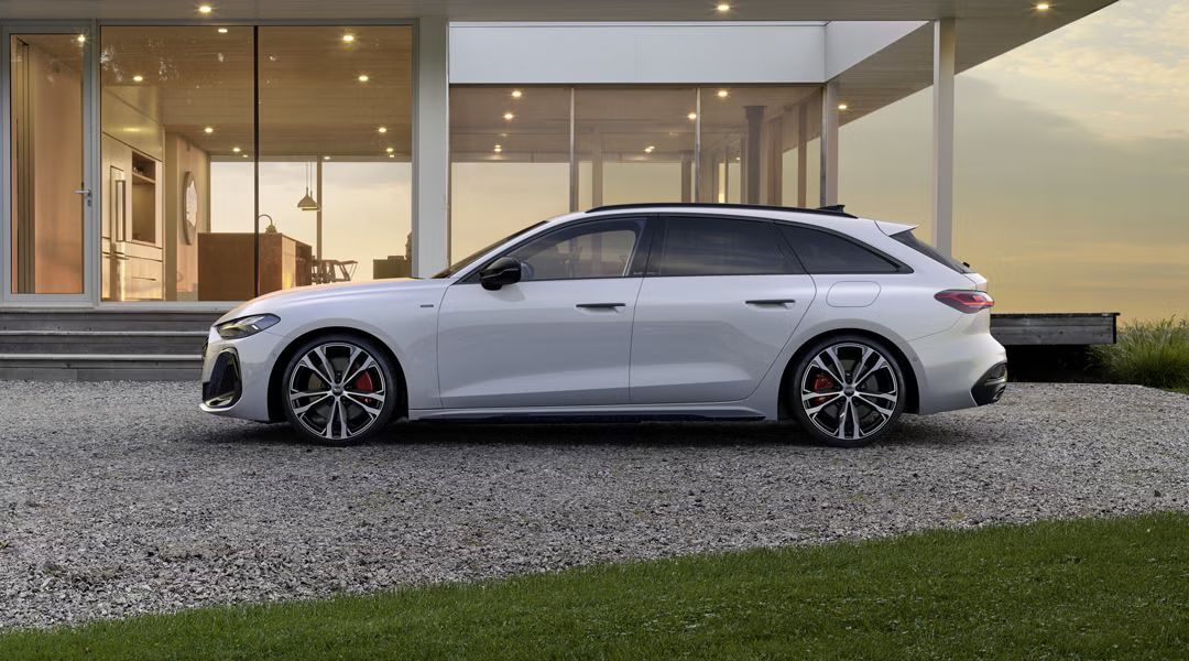 Der A5 Avant e-hybrid im Seitenprofil vor einem modernen Wohnhaus.