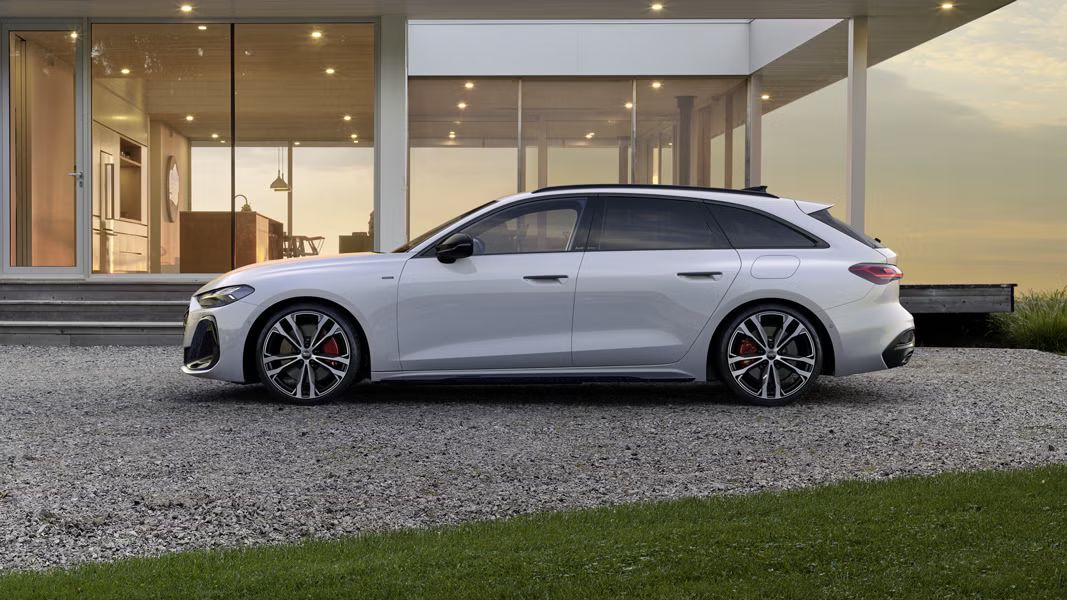 Der A5 Avant e-hybrid im Seitenprofil vor einem modernen Wohnhaus.