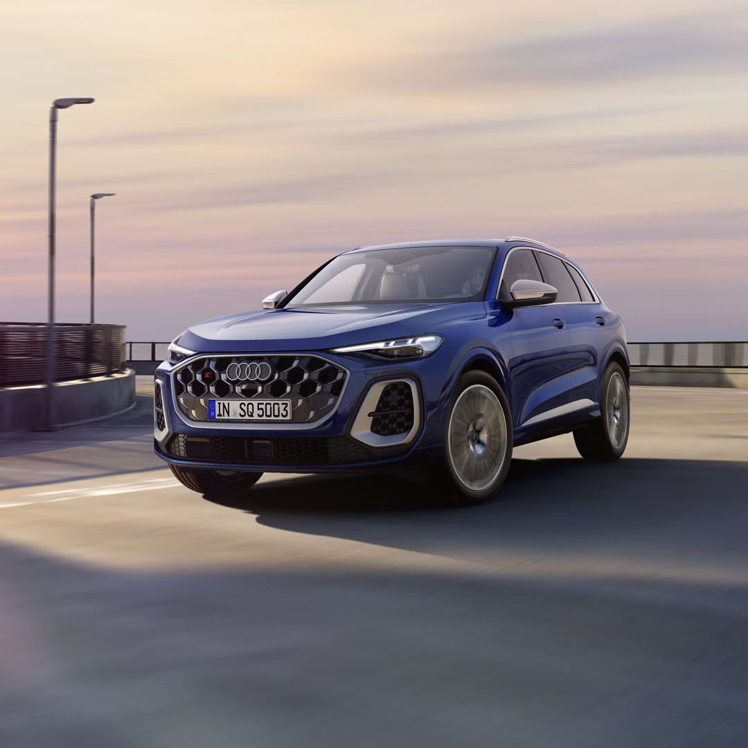 Der SQ5 SUV in dunkelblau fährt über eine Brückenstraße. Am Steuer befindet sich eine junge Frau.