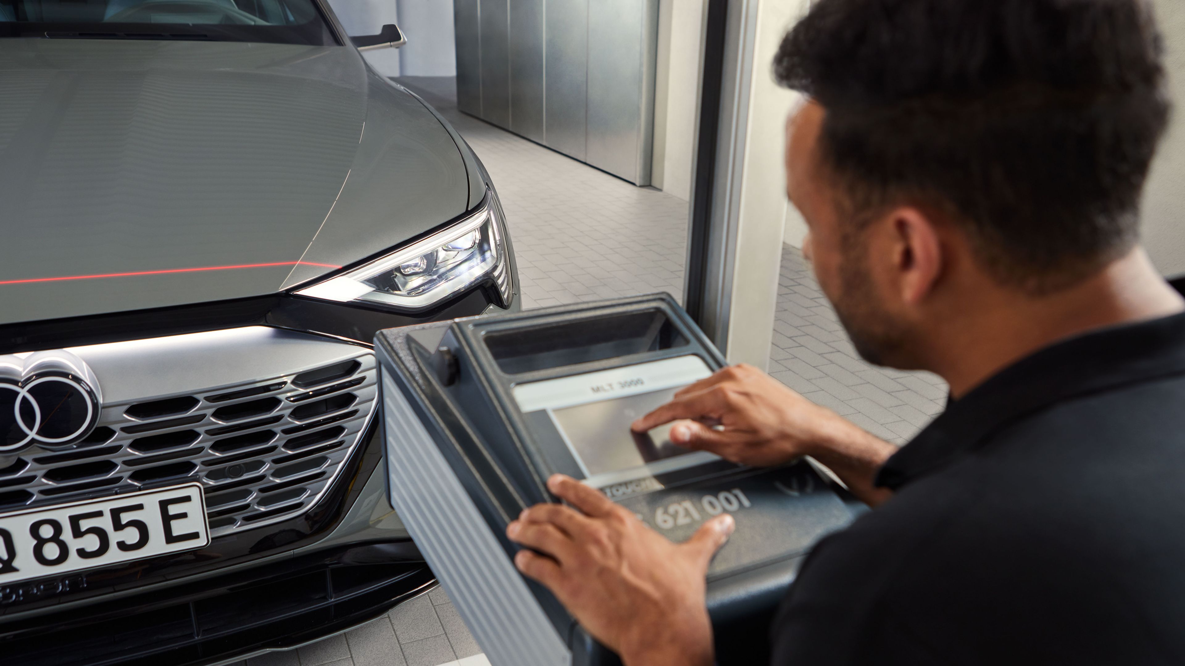 Ein Audi Techniker überprüft mit einem Laser die Oberfläche eines Audi Elektroautos