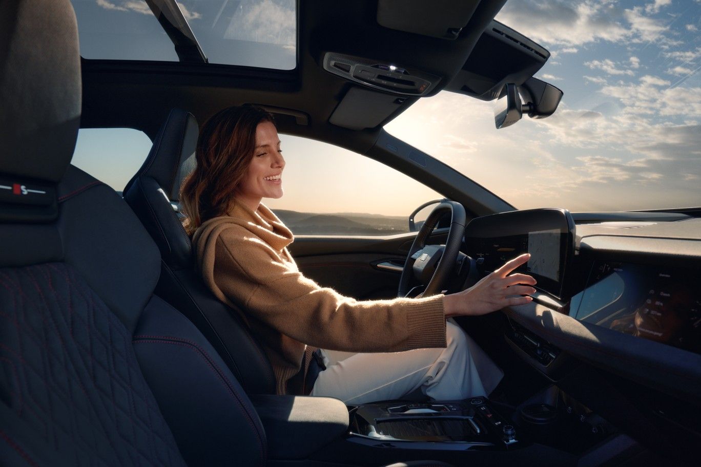 Eine Frau bedient während der Fahrt den Touch Screen von ihrem Audi.