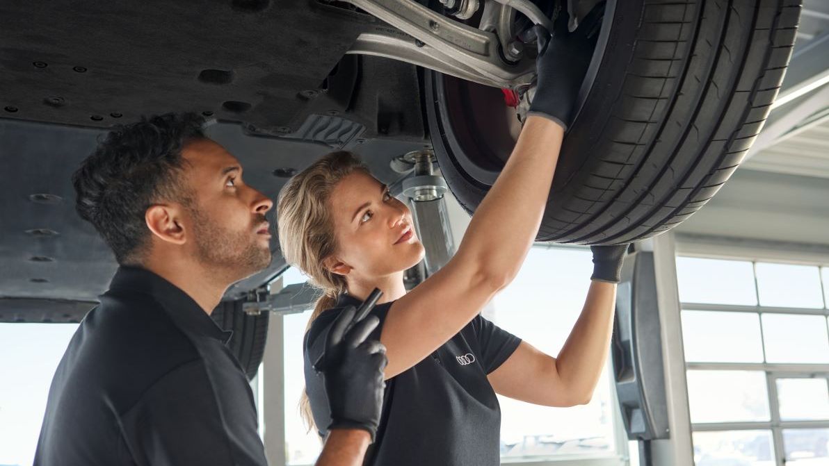 Zwei Audi Mechaniker kontrollieren die Radaufhängung bei einem Audi