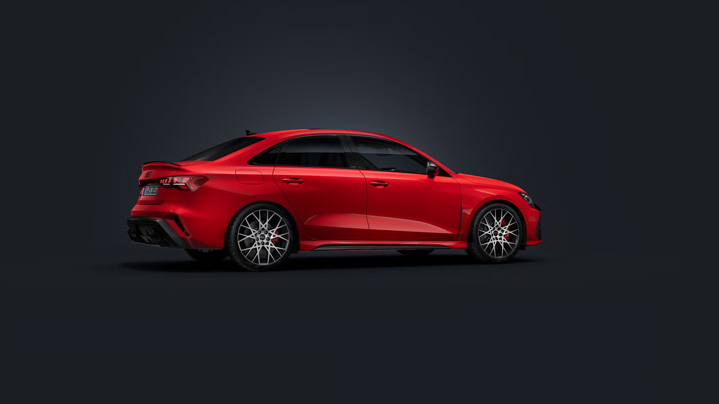 Die Audi RS 3 Limousine steht auf dunklem Hintergrund und dreht sich leicht auf die rechte Seite.