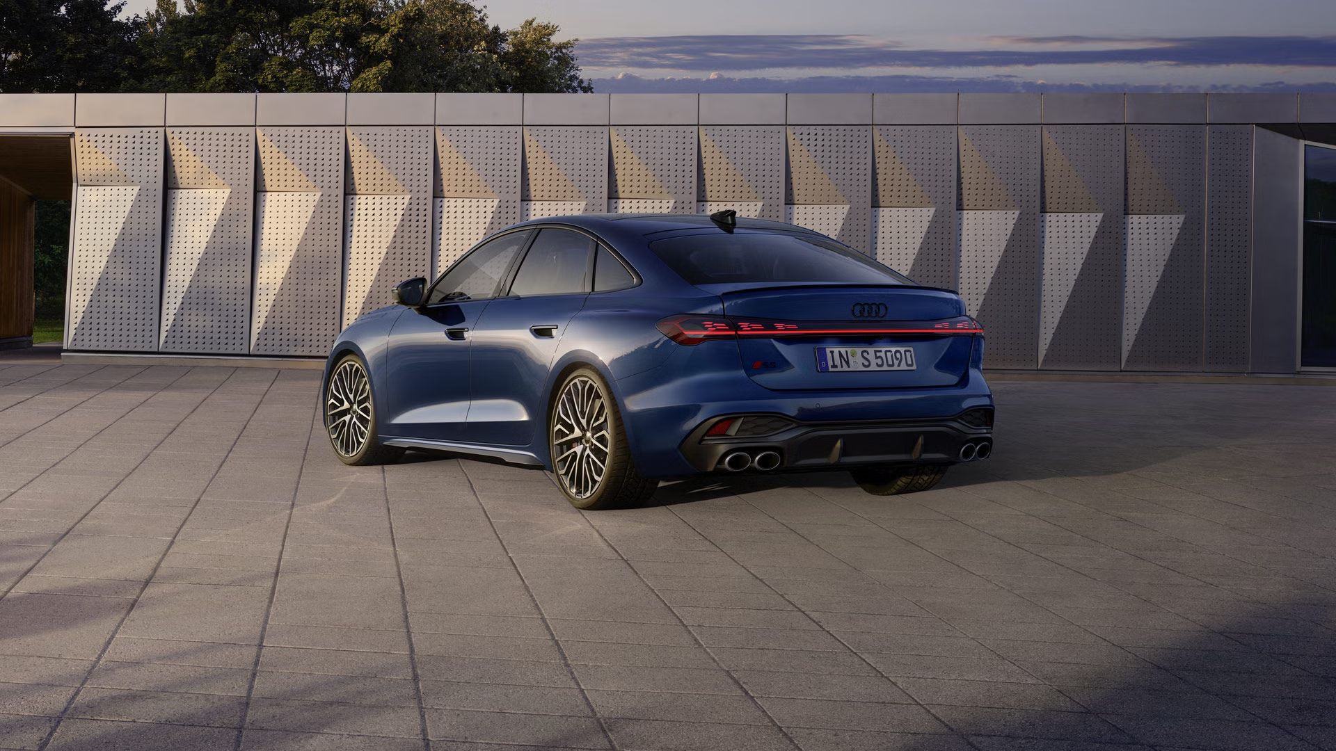 Die S5 Limousine in dunkelblau steht schräg vor einer Gebäudefassade und wird dabei vom Sonnenlicht angestrahlt.