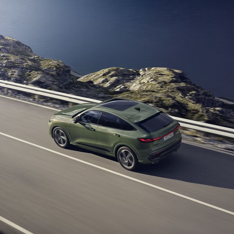 Der Q5 Sportback im schrägen Seitenprofil von oben betrachtet. Das Fahrzeug fährt auf einer Gebirgsstraße.