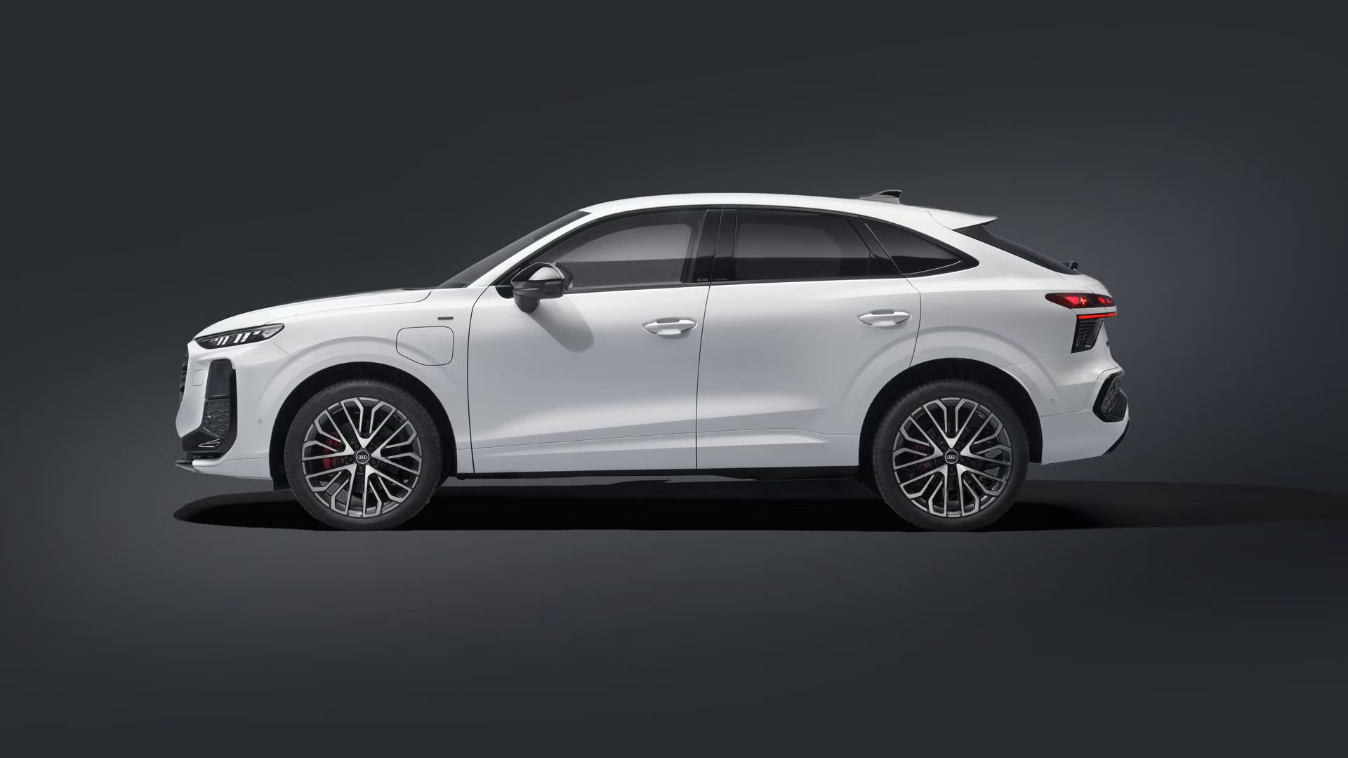 Seitliche Ansicht des Q3 Sportback e‑hybrid in dunkler Umgebung.