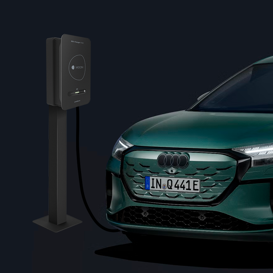 Der Q4 Sportback e-tron schräg von vorn auf dunklem Hintergrund, dahinter eine moderne Ladesäule.