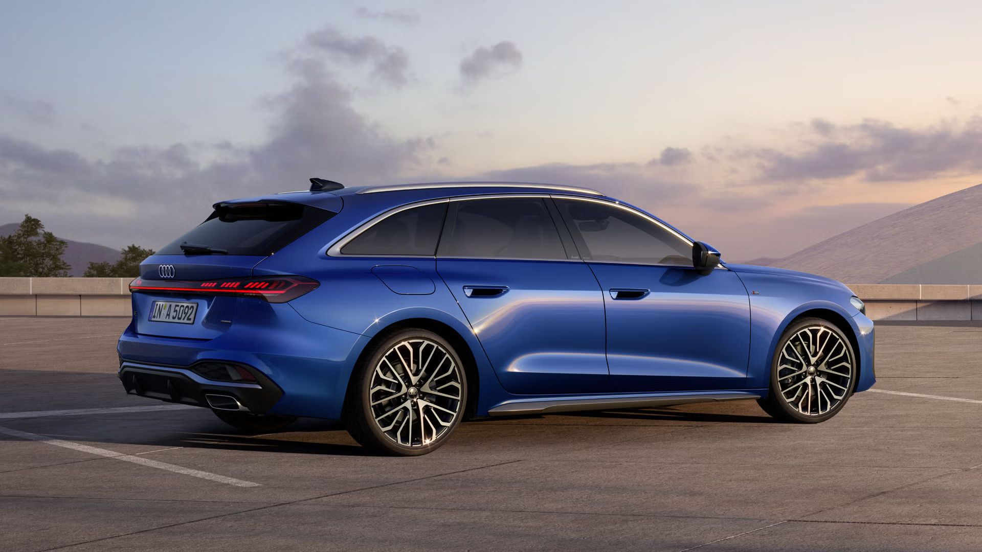 Der A5 Avant in Ascariblau Metallic steht im schrägen Seitenprofil auf einem großen Parkplatz. 