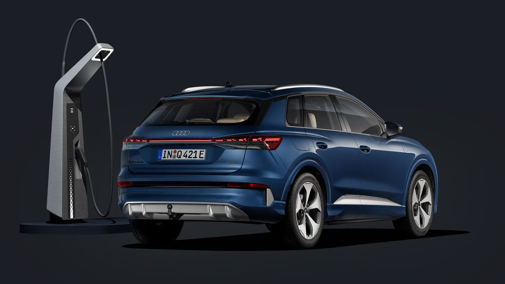 Der Q4 SUV e-tron von schräg hinten auf dunklem Hintergrund, flankiert von einer modernen Ladesäule.