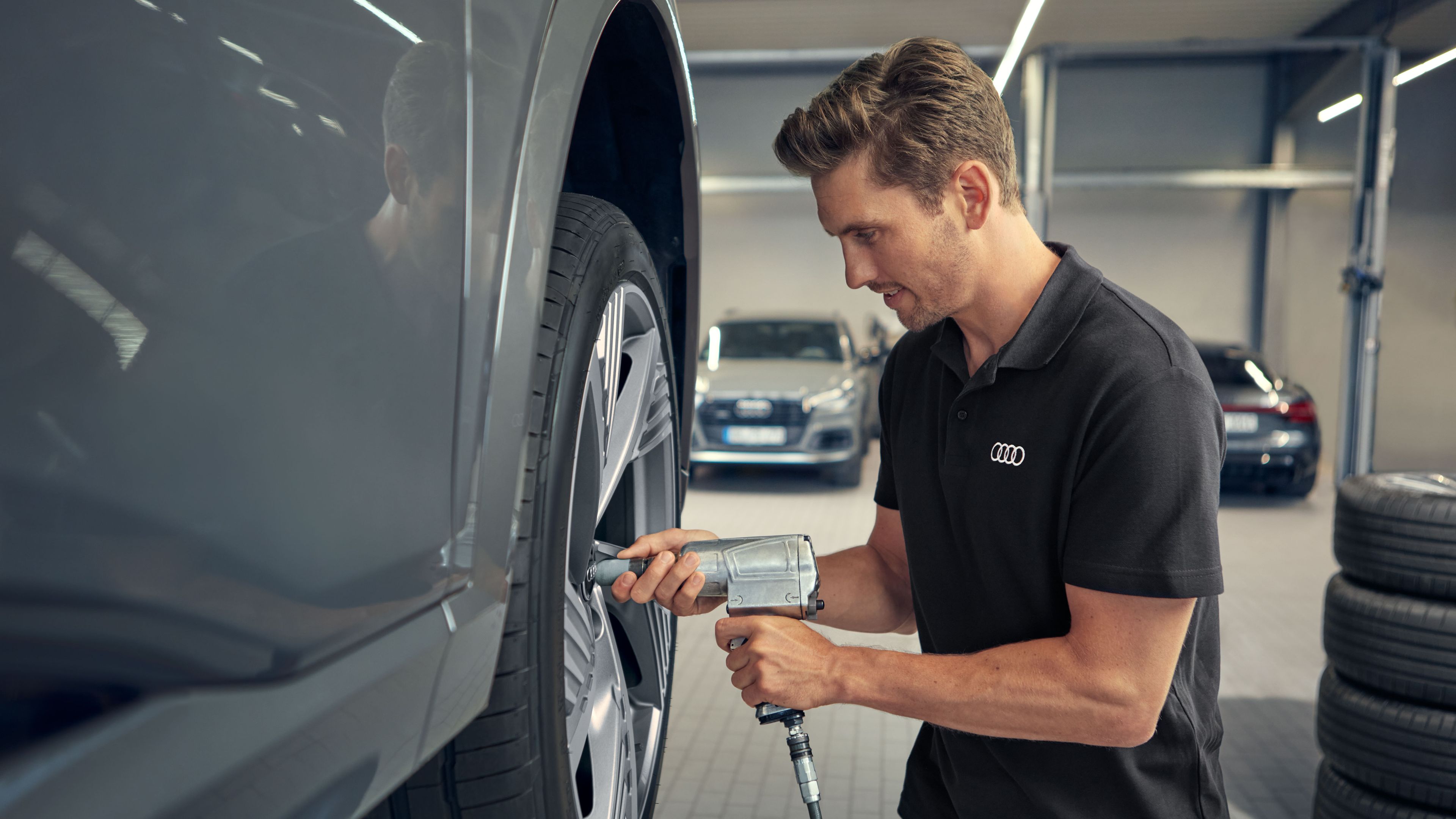 Ein Audi Service Techniker befestigt die Räder an einem Audi Elektroauto