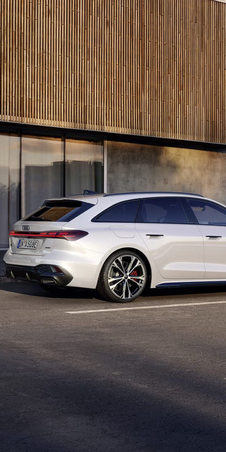 Der A5 Avant e-hybrid steht im schrägen Seitenprofil vor der Fassade eines großen Gebäudes.