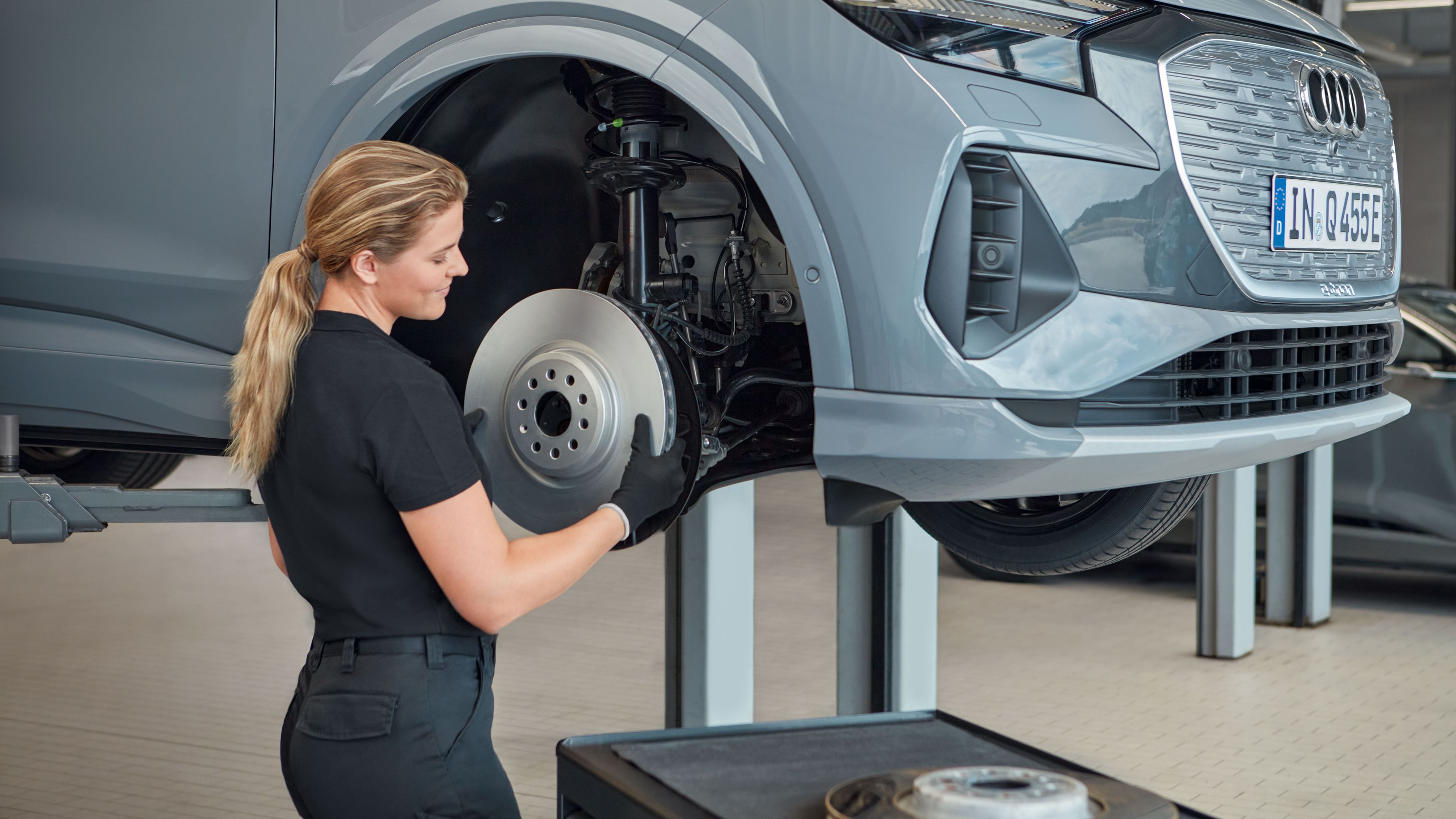 Eine Audi Service Technikerin wechselt die Bremsscheiben bei einem Audi Elektroauto