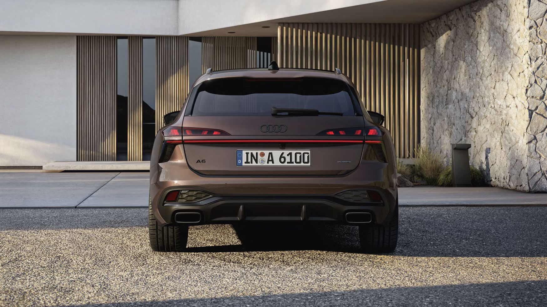 Heckaufnahme des A6 Avant, der auf einer Kiesfläche vor einer Fassade mit Holzvertäfelung und hohen Fenstern steht.
