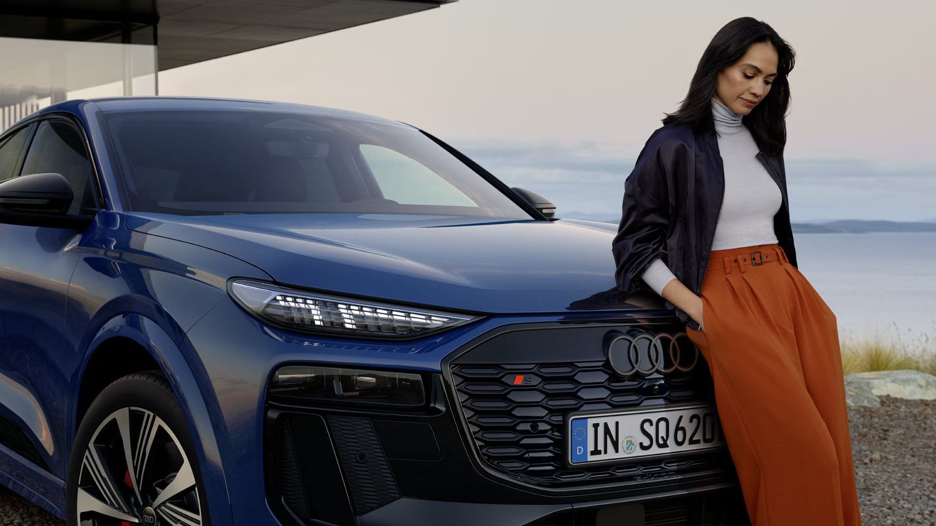 Eine Frau lehnt an einem blauen Audi SQ6 Sportback e-tron