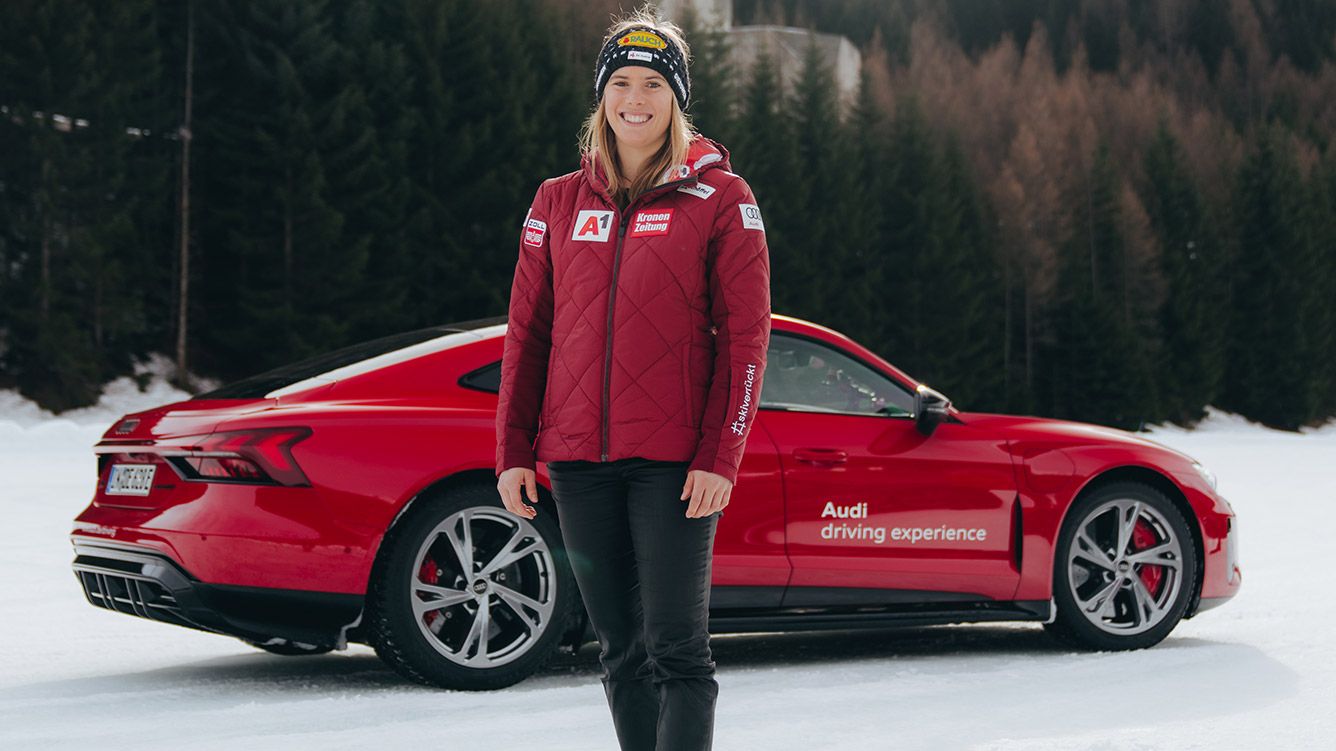 Skirennläuferin Katharina Liensberger steht im Schnee vor einem roten Audi.