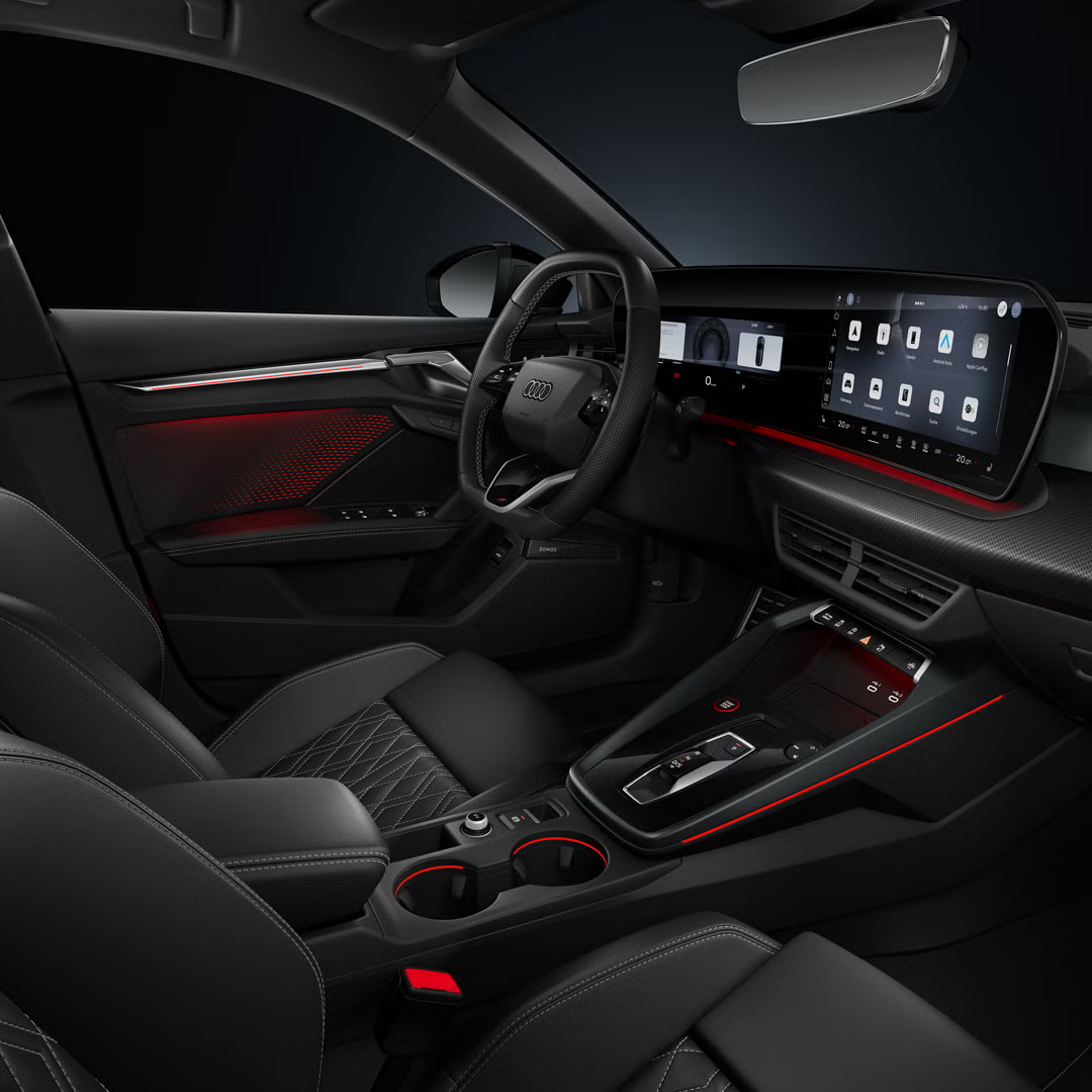 Blick von der Beifahrerseite auf das Cockpit mit Sportlenkrad, beleuchteter Mittelkonsole und Ambiente-Licht.