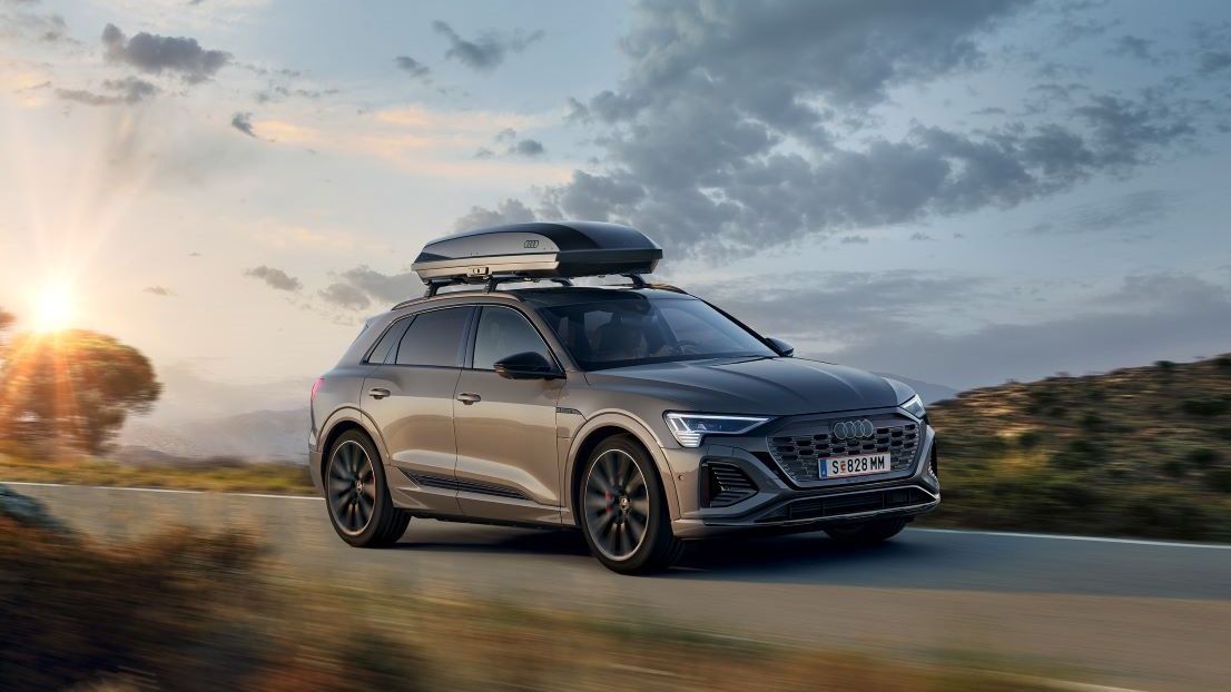 Ein Audi Q8 mit Dachbox in Fahrt auf einer Landstraße.
