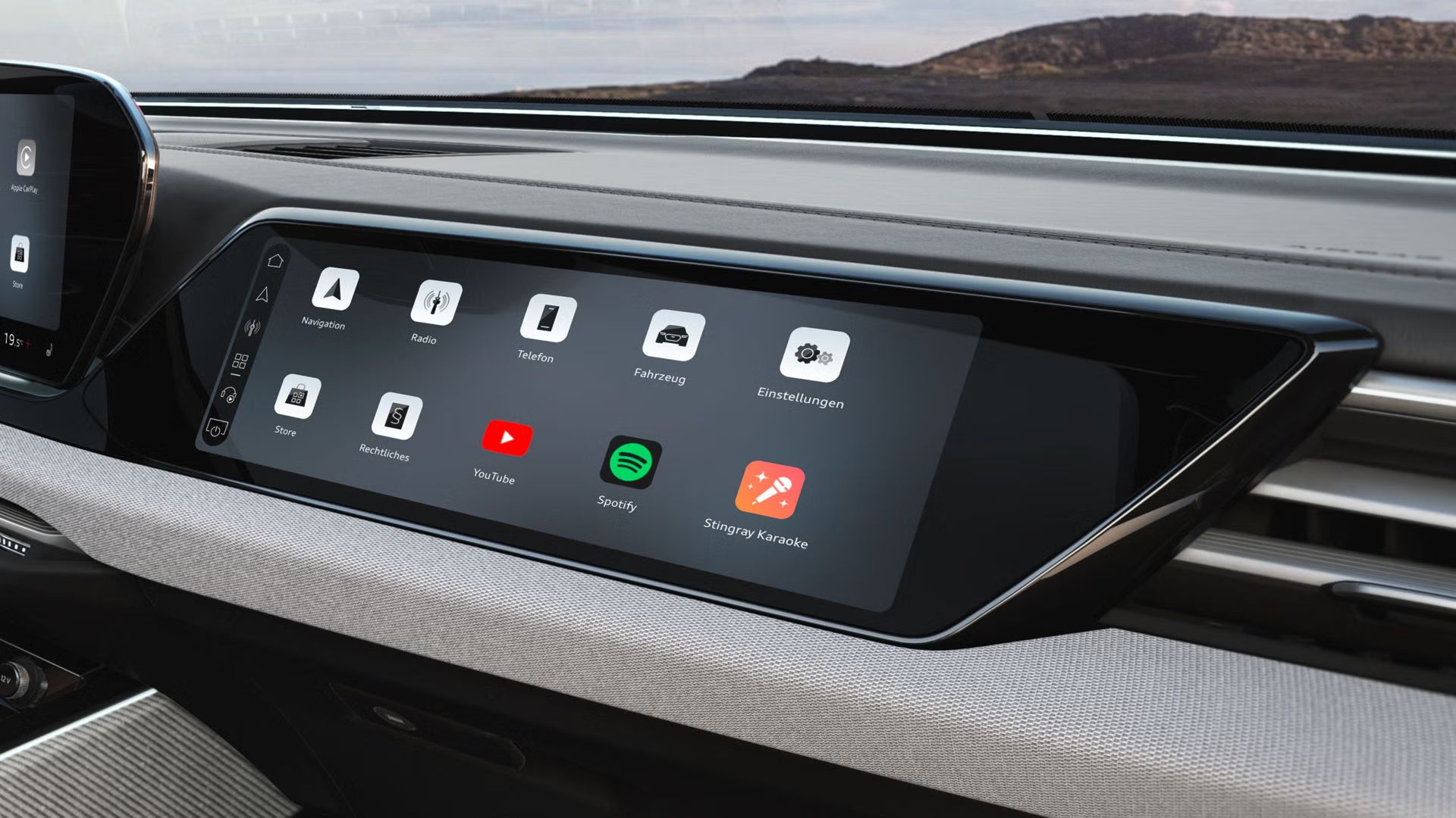 Nahaufnahme des Beifahrerdisplays. Auf diesem wird eine Übersicht der vorhandenen Apps und Funktionen gezeigt.
