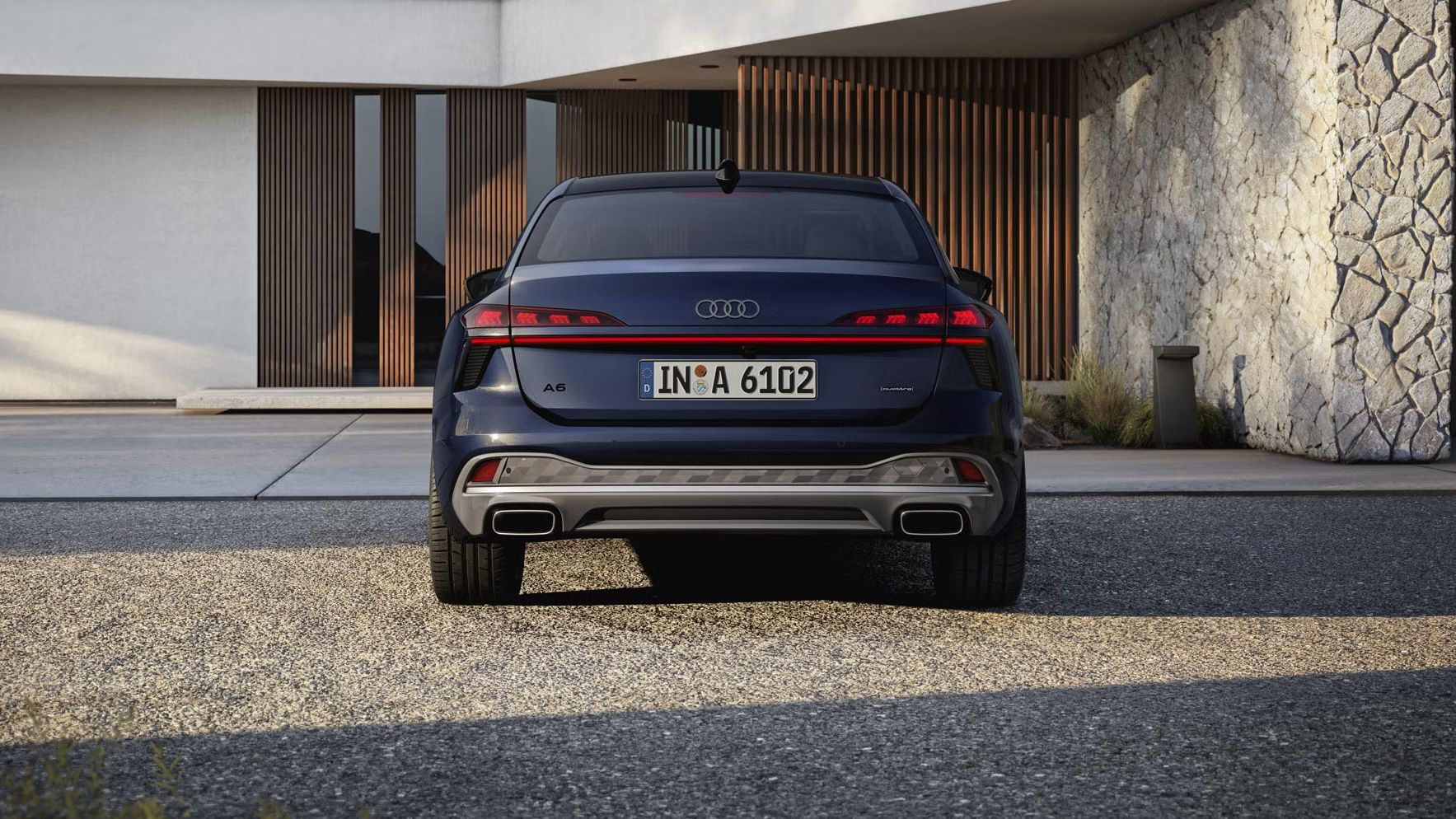 Die A6 Limousine in der Heckperspektive. Das Fahrzeug steht einem modernen Haus zugewandt.