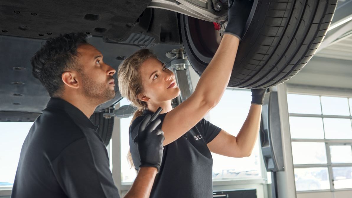 Zwei Audi Mechaniker kontrollieren die Radaufhängung bei einem Audi