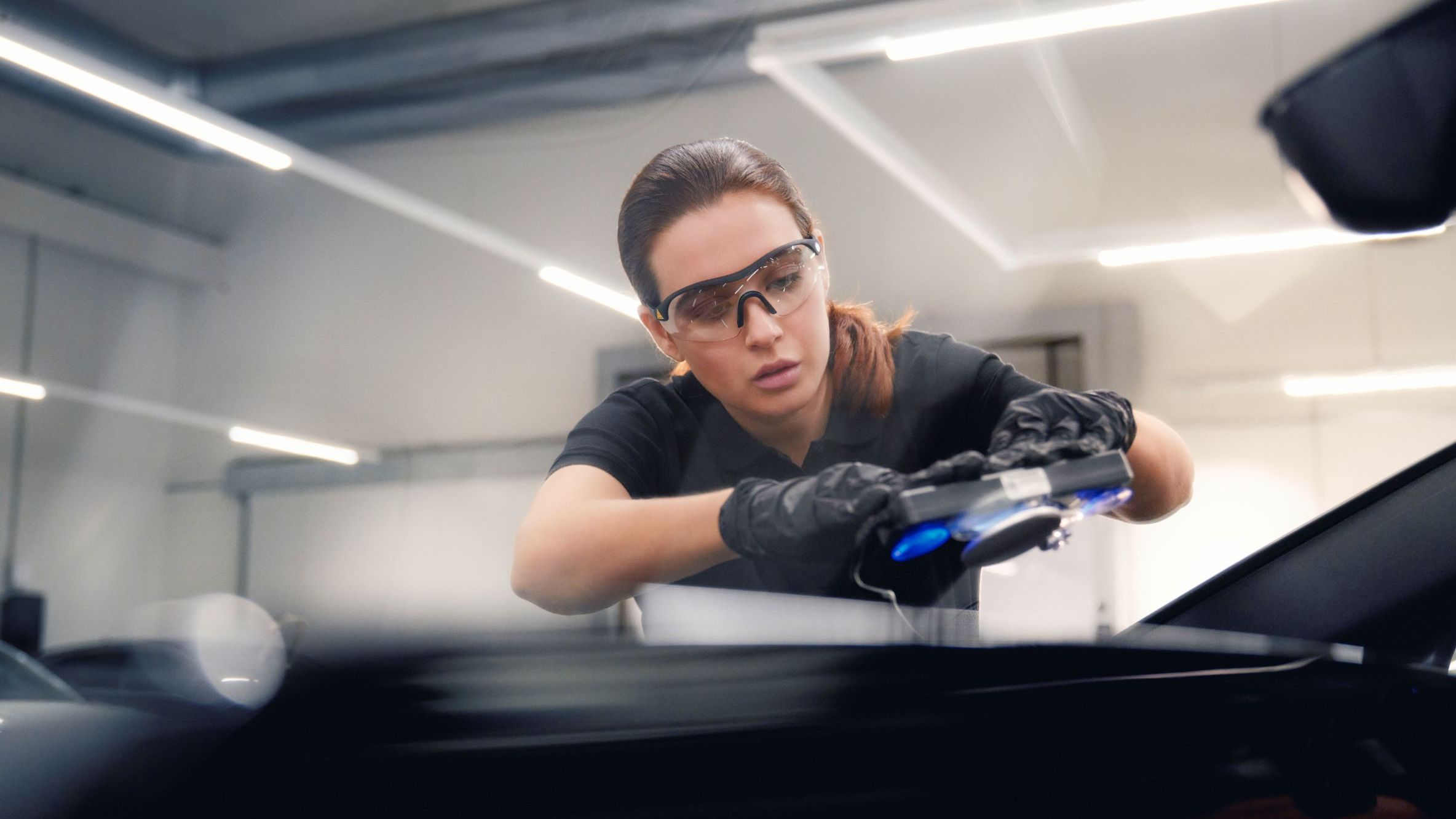 Eine Audi Mechanikerin bei der Reparatur einer Windschutzscheibe