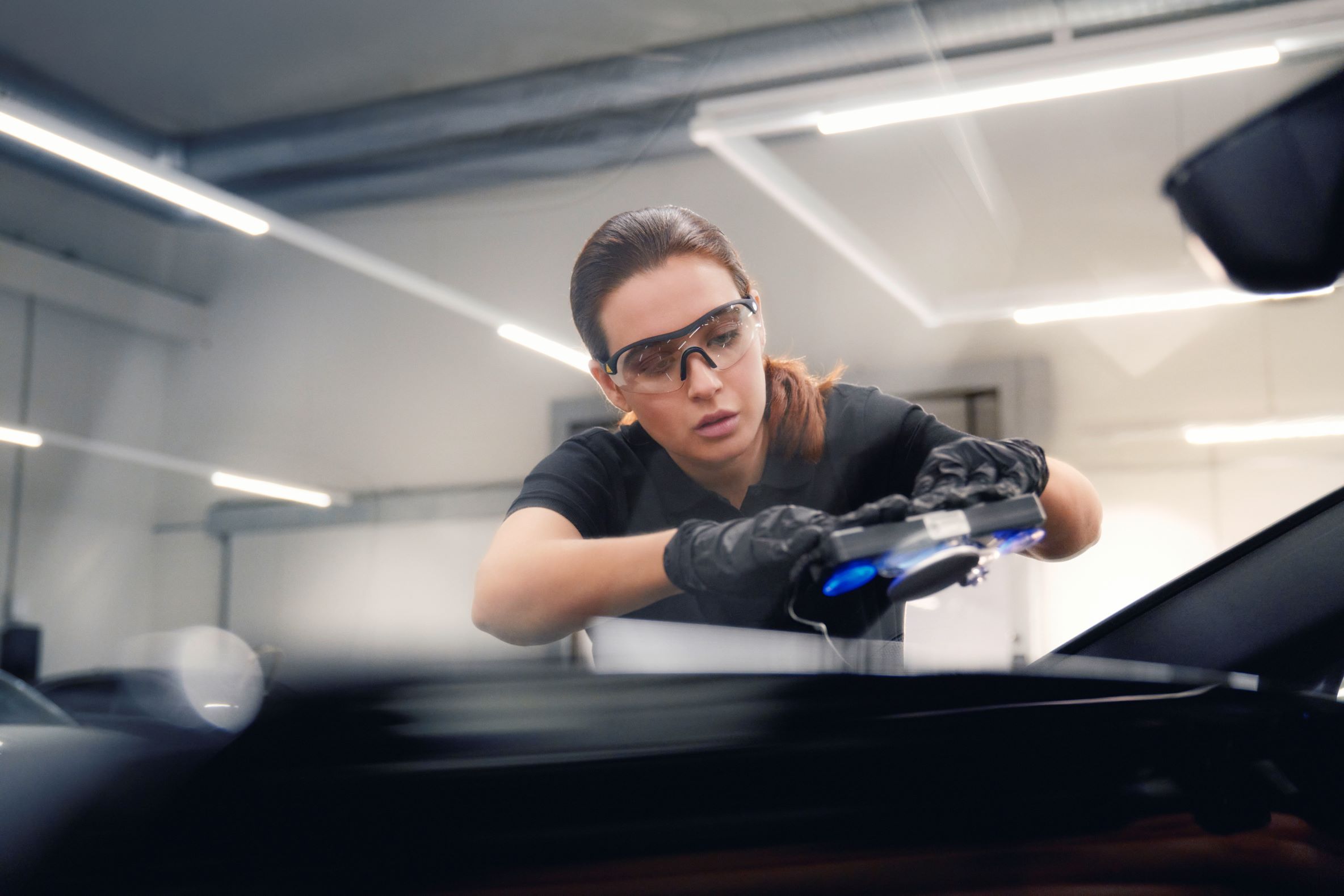 Eine Audi Mechanikerin bei der Reparatur einer Windschutzscheibe