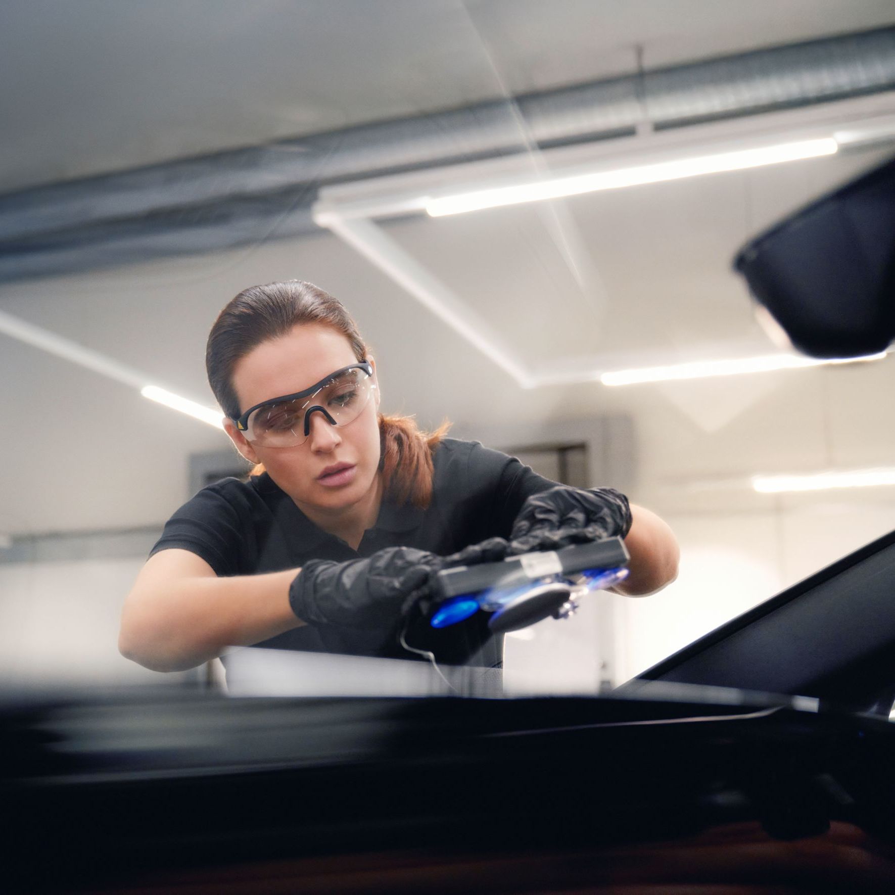 Eine Audi Mechanikerin bei der Reparatur einer Windschutzscheibe