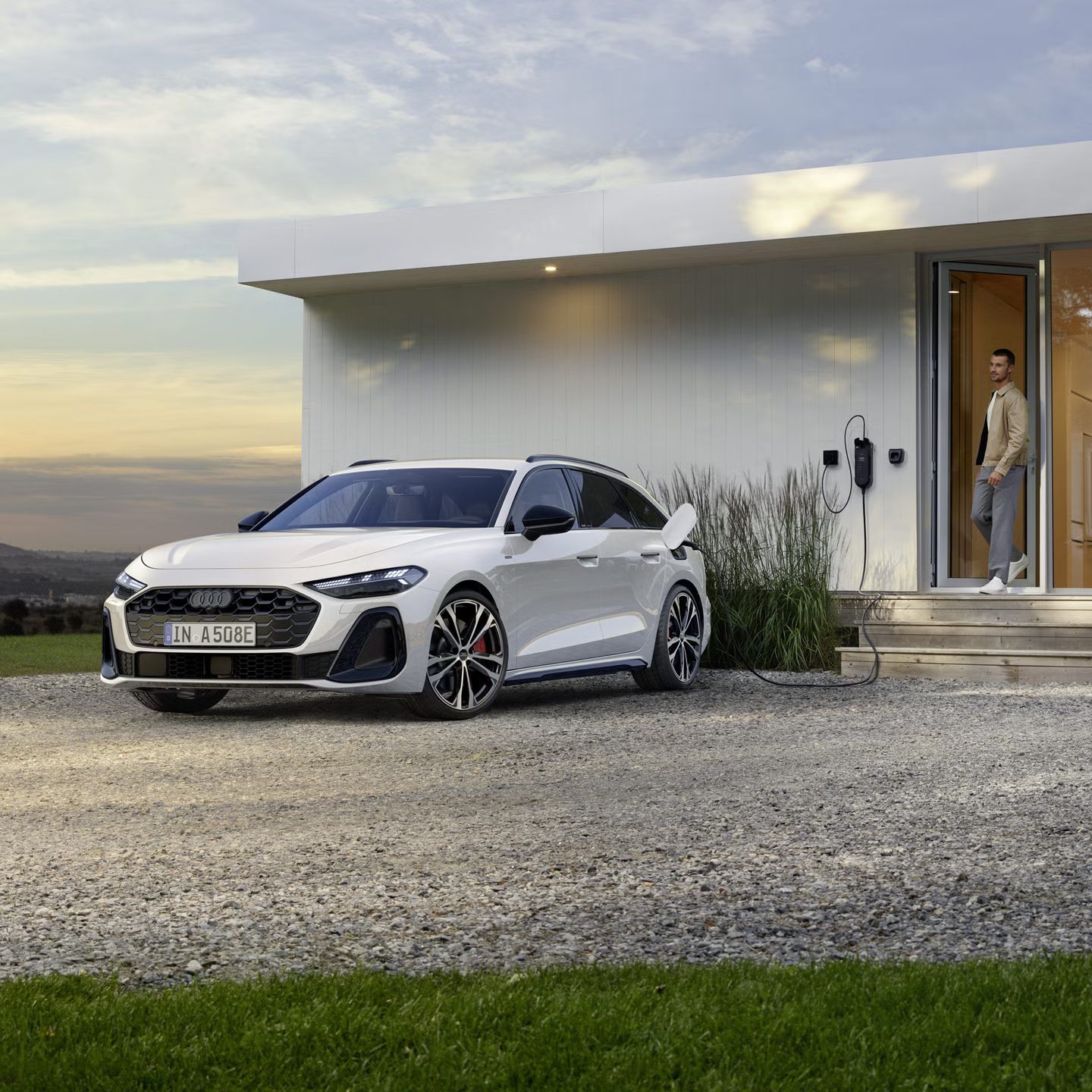 Ein weißer Audi A5 Avant e-hybrid lädt an einer heimischen Wallbox