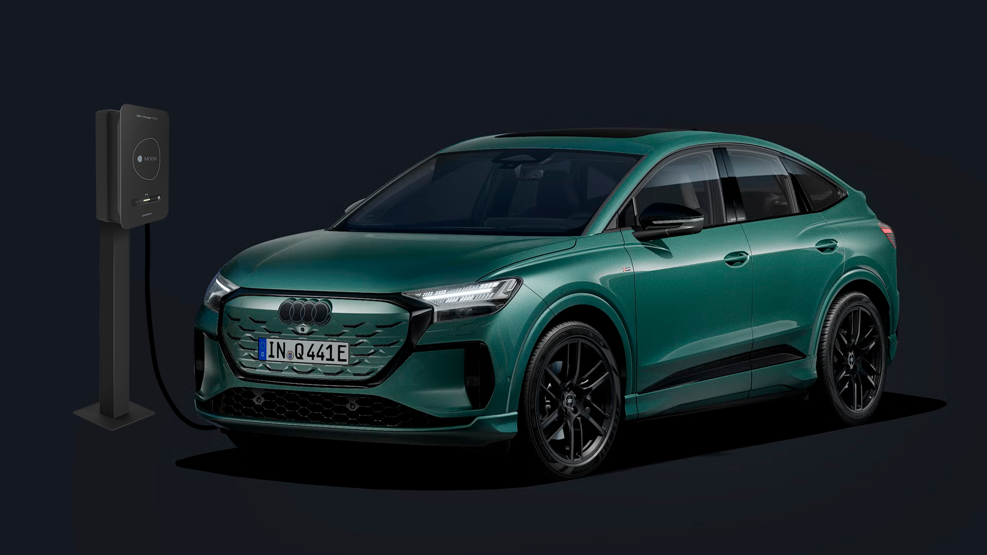 Der Q4 Sportback e-tron schräg von vorn auf dunklem Hintergrund, dahinter eine moderne Ladesäule.