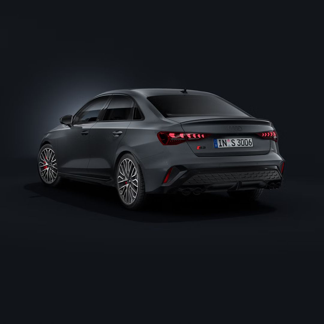 Die Audi S3 Limousine schräg von hinten auf dunklem Hintergrund.