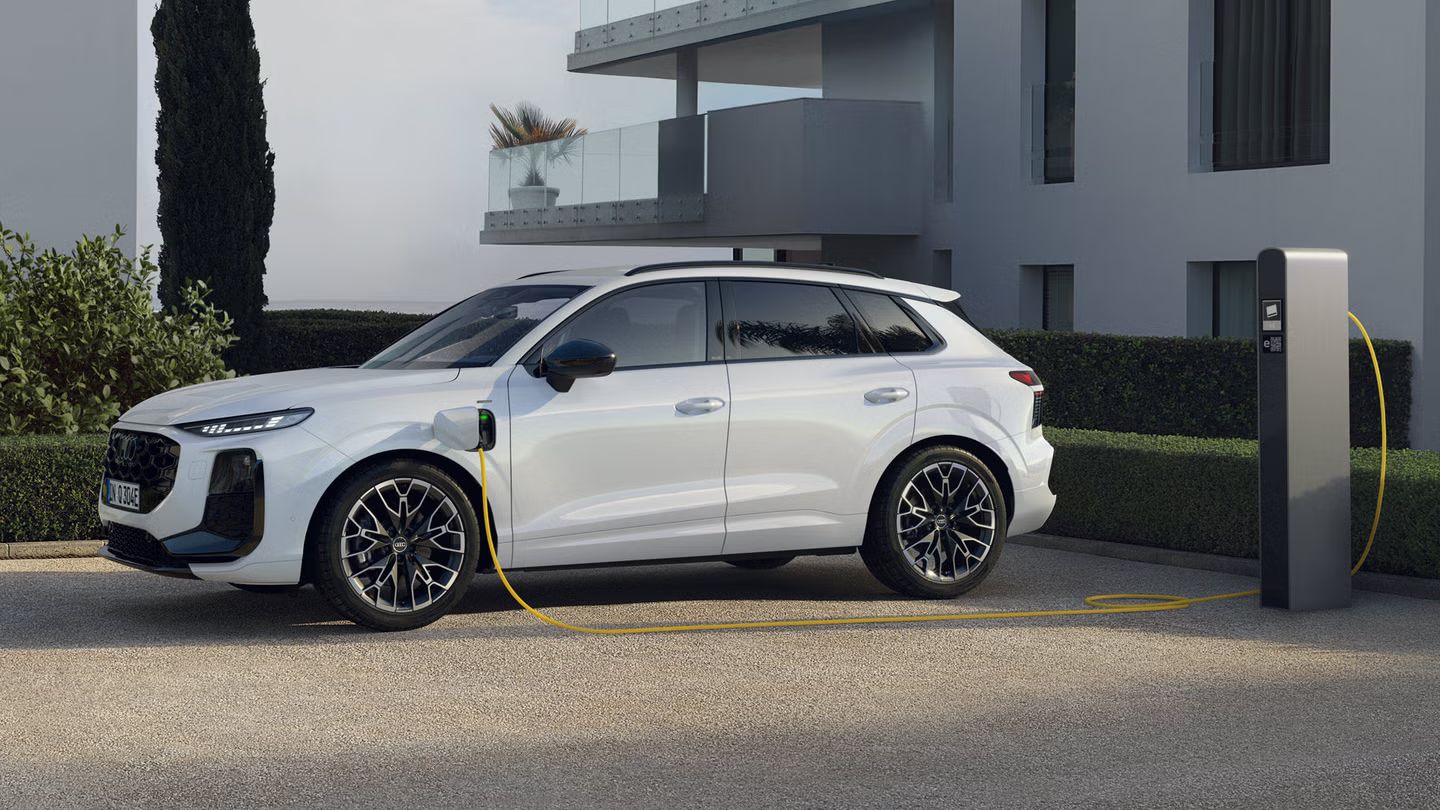 Weißer Audi Q3 SUV e-hybrid steht an der Ladesäule vor einem Gebäude