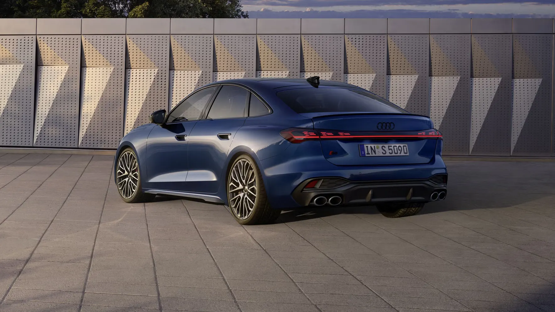 Die S5 Limousine in dunkelblau steht schräg vor einer Gebäudefassade und wird dabei vom Sonnenlicht angestrahlt.