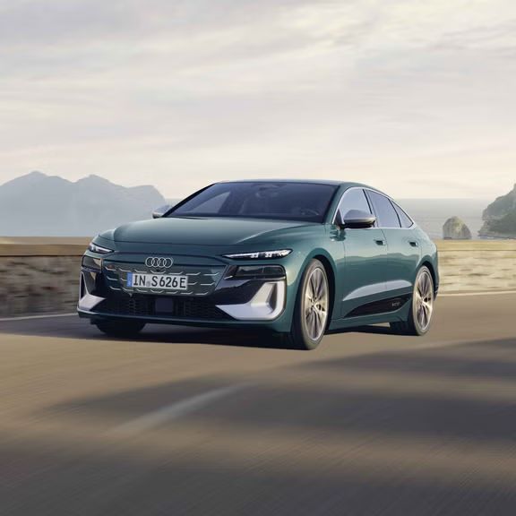 Der S6 Sportback e-tron im schrägen Frontprofil, während er eine Küstenstraße entlangfährt.