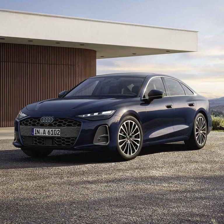 Die A6 Limousine steht im schrägen Frontprofil vor einem modernen Haus. 