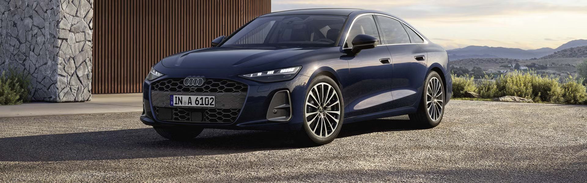 Die A6 Limousine im schrDie A6 Limousine steht im schrägen Frontprofil vor einem modernen Haus. ägen Frontprofil vor einem modernen Haus. 